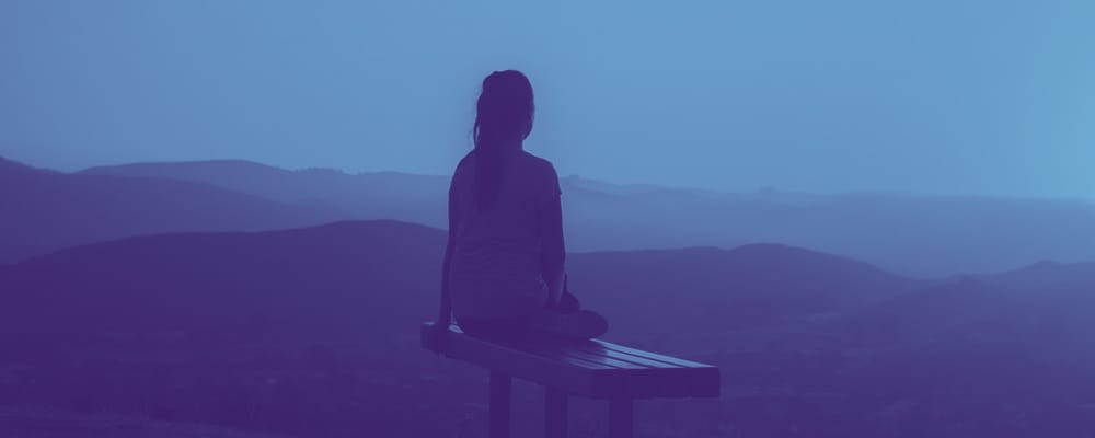 woman sitting on a bench overlooking mountains